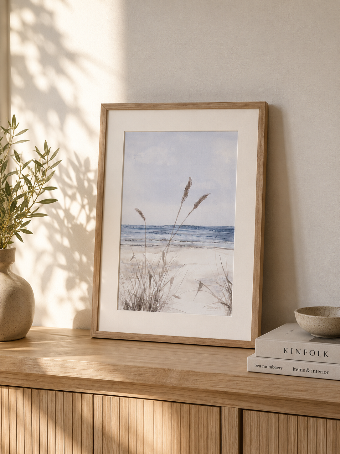 Minimal watercolor painting of a quiet beach shoreline with coastal grasses and soft blue sea, airy seaside artwork by Martina Hastal.